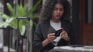A black woman is getting ready for work in an office uniform in a public downtown area, carrying all her work equipment including a computer and a phone. video