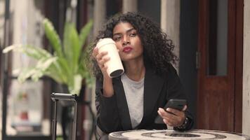 A black woman is getting ready for work in an office uniform in a public downtown area, carrying all her work equipment including a computer and a phone. video