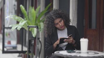 A black woman is getting ready for work in an office uniform in a public downtown area, carrying all her work equipment including a computer and a phone. video