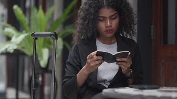 A black woman is getting ready for work in an office uniform in a public downtown area, carrying all her work equipment including a computer and a phone. video