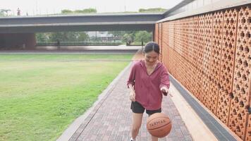 A woman plays basketball alone in a public area, having fun and practicing at the same time. video