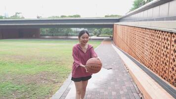 A woman plays basketball alone in a public area, having fun and practicing at the same time. video