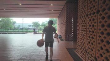 A man plays basketball alone in a public area, having fun and practicing at the same time. video