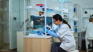 Microbiologist working for new vaccine in modern laboratory looking at samples under microscope. Multiethnic team examining virus evolution using high tech and chemistry tools for scientific research. photo
