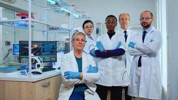 Professional multiethnic medical staff looking at camera in modern equipped lab. Team of doctors examining virus evolution with high tech, chemistry tools for scientific research, vaccine development photo