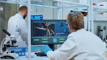 Medical research scientist typing codes on pc in biological applied science modern equipped laboratory. Lab engineers in white coats conducting experiment for vaccine development against covid19 virus photo
