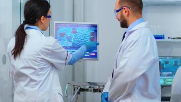 Scientist team arguing in front of computer looking at virus development in modern equipped laboratory. Multiethnic stuff analysing vaccine evolution using high tech for researching treatment. photo