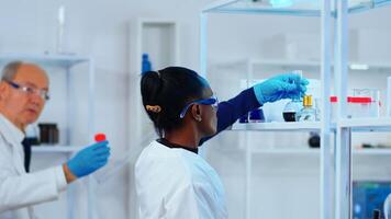 African woman chemist researcher using glass equipment in modern equipped laboratory. Multiethnic stuff examining vaccine evolution using high tech and technology researching treatment against virus. photo