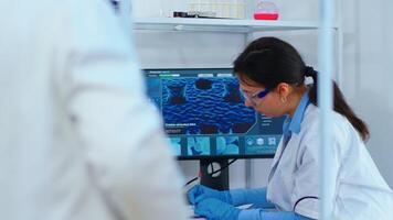 Chemist nurse working on computer in scientific modern equipped laboratory. Multiethnic stuff examining vaccine evolution using high tech and technology researching treatment against covid19 virus photo