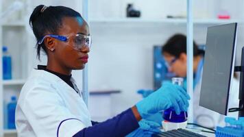 Black woman biologist researching using computer in modern equipped laboratory. Multiethnic stuff examining vaccine evolution using high tech and technology researching treatment against covid19 virus photo