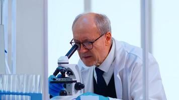 Senior lab technician examining samples and liquid using microscope in equipped laboratory. Scientist working with various bacteria, tissue and blood samples, pharmaceutical research for antibiotics photo