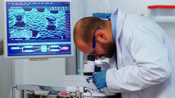 Biological technology scientist using microscope doing research for new vaccine in pharmaceutical labolatory. Coworkers examining virus evolution using high tech researching diagnosis against covid19 photo