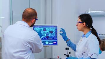 Group of scientists working in modern equipped laboratory pointing on computer desktop. Team of doctors examining vaccine evolution using high tech researching diagnosis against covid19 virus photo