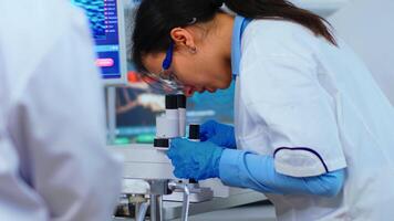 Biochemical research scientist team working with microscope for vaccine development in pharmaceutical labolatory. Stuff examining virus evolution using high tech researching diagnosis against covid19 photo