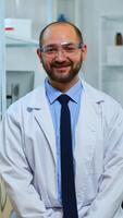 Experienced man scientist looking at camera smiling in modern equipped lab. Multiethnic team examining virus evolution using high tech and chemistry tools for scientific research, vaccine development photo