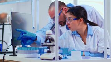 Chemist nurse explainig to doctor vaccine development in modern equipped laboratory pointing on computer desktop. Team of doctors examining virus evolution using high tech researching diagnosis photo