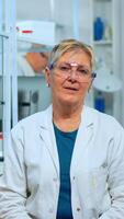 Portrait of senior scientist woman looking at camera in modern equipped lab. Multiethnic team examining virus evolution using high tech and chemistry tools for scientific research, vaccine development photo