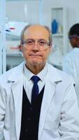 Senior chemist sitting in modern equipped lab looking satisfied at camera. Multiethnic team examining virus evolution using high tech and chemistry tools for scientific research, vaccine development photo
