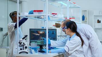 Team of microbiology scientists discussing about virus development in modern equpped laboratory using computer analysing test blood samples and develop vaccine, drugs and antibiotics against covid-19. photo