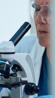 Woman research scientist looking at samples under microscope in modern equipped laboratory. Eldery doctor working with various bacteria, tissue and blood tests, pharmaceutical research for antibiotics photo