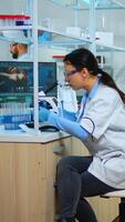 Microbiologist working for new vaccine in modern laboratory looking at samples under microscope. Multiethnic team examining virus evolution using high tech and chemistry tools for scientific research. photo