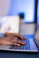 Close up of african worker hands typing on laptop computer keyboard in home office. Employee using modern technology network wireless doing overtime. photo
