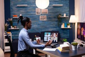 Dark skinned business woman doing remote work speaking with coworkers during call. Using modern technology network wireless talking on virtual meeting doing overtime. photo