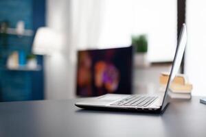 Open laptop sitting on desk in home office. Cozy home living room with nobody in it with beautiful interior design. photo