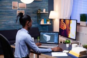 African entrepreneur developer working from home office late at night. Industrial black female engineer studying prototype idea on personal computer showing software on device display photo