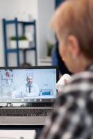Old patient talking with doctor on virtual call showing pills bottle. Elderly woman on telemedicine online conference call with practitioner doctor using modern healthcare technology, web diagnosis photo