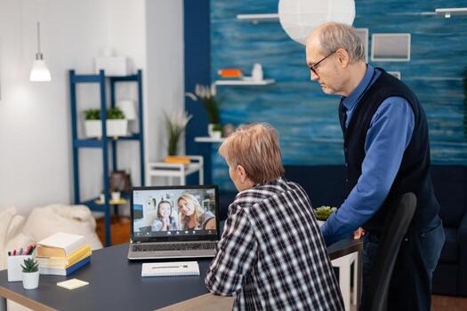 Old father and mother talking with daughter and niece. Happy grandparent communicating with family via online web internet conference using modern internet technology while sitting in the living room photo