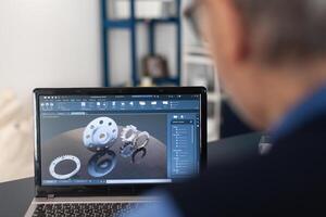 Engineer designed gears parts using professional software. Experienced engineer working from home office on mechanical project using laptop computer technology and wife is reading a book on sofa. photo