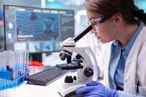 Pharmacy scientist working with professional microscope in technology lab. Modern laboratory with research equipment for virus study and vaccine science development. photo