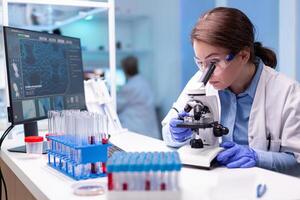 Scientist looking into microscope in virus research laboratory with pharmacy development equipment. Woman working on science vaccine chemistry experiment in modern lab, analyzing pharmaceutical work photo