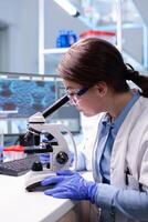 Biotechnologist woman scientist researching with a microscope in pharma lab. Modern laboratory for scientific research with professional equipment for virus study and vaccine science development photo