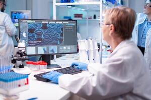 Medical scientist analyzing a test into computer for hospital expertise. Professional senior doctor examining vaccine evolution using high tech for scientific research, treatment development against covid19 photo