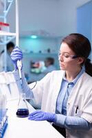 Scientist looking into micropipette for biology test . Woman research a new experiment in modern lab, analyzing pharmaceutical work with modern equipment. photo
