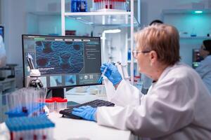 Professional doctor scientist looking in computer for medical experiment. Chemist researcher working in laboratory with test tube to discovery vaccine against coronavirus photo
