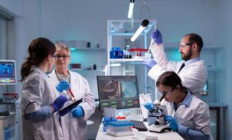 Team of scientific investigators conducting experiments in lab using microscope and micropipette. Laboratory for disease research with professional equipment for virus study and diagnosis development photo