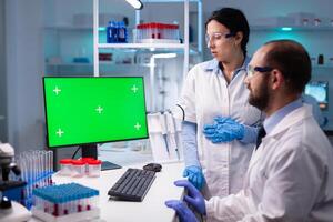 Modern medical research laboratory with two scientists using computer with green chroma key screen. Doctors specialists discovering scientifc experiment with technology equipment industry photo