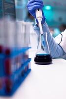 Close up of micropipette dipping in test tube for science experiment. Pharmacy scientist doctor discovery scientific disease with biotechnology professional equipment. photo