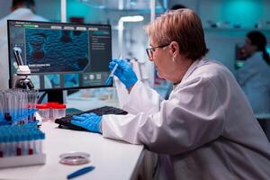 Scientist typing results of science analysis holding test tube with sample, healthcare, chemistry. Chemist researcher working in laboratory with test tube to discovery vaccine against coronavirus. photo