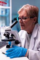 Close up of doctor chemist scientist analyzing sample in lab coat with microscope. Laboratory for scientific research with professional equipment for virus study and diagnosis biotechnolog development. photo