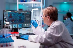 Biotechnologist senior scientist researching with test tube in pharma lab. Chemist researcher working in laboratory with test tube to discovery vaccine against coronavirus. photo