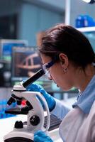 Scientist examining researching analyzing virus loking through microscope. Research chemists working in lab with high tech analyzing blood and genetic material samples discovery, photo