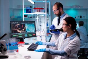 Team of researcher working in science laboratory, biochemistry analyzing sample data on computer. Doctors specialists discussing innovative treatment using high tech technology equipment for healthcare. photo