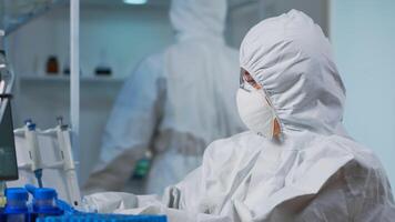 Close up of scientist in protection suit typing on pc working in medical laboratory, developing inovative drugs. Doctor using high tech, chemistry tools for scientific research, against new virus photo