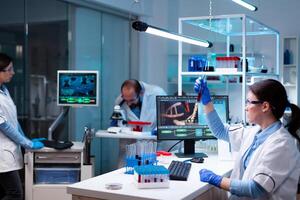 Scientist analyzing blood sample in test tube and team doing research with dna image. Chemists in pharmaceutical lab examining sample for medical experiment with technology for medicine industry. photo