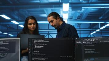 Developer in server hub using laptop to present manager plan of repairing equipment storing datasets. Specialist uses notebook to explain team leader ways of fixing rigs doing computational operations photo