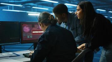 Multiethnic programmer team in server farm workspace surprised by data threatened by hacking attack on computers. Diverse colleagues scrambling to protect data center from unauthorized access photo